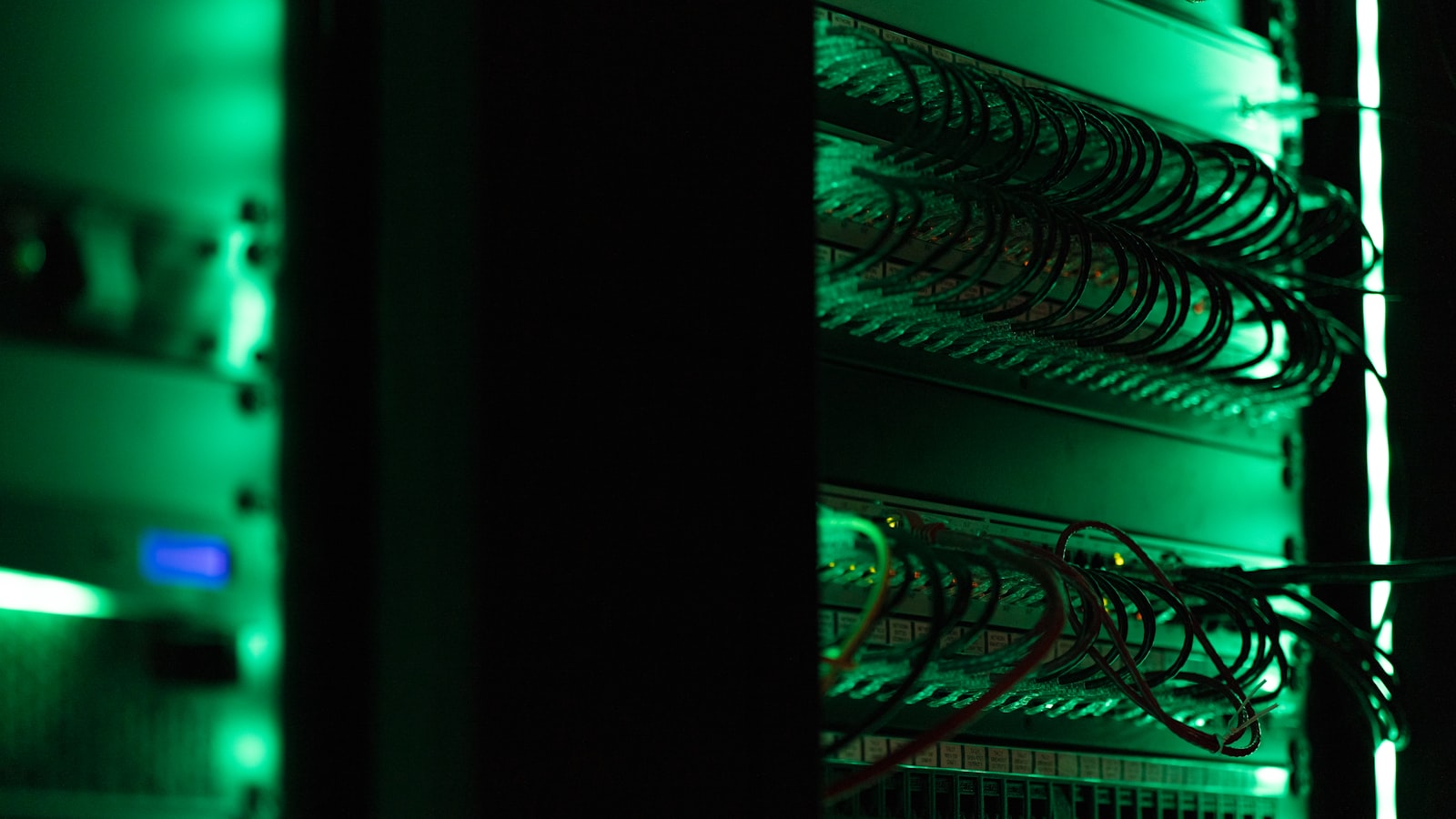 Een donker serverrack verlicht door groene statusleds en gebundelde bekabeling